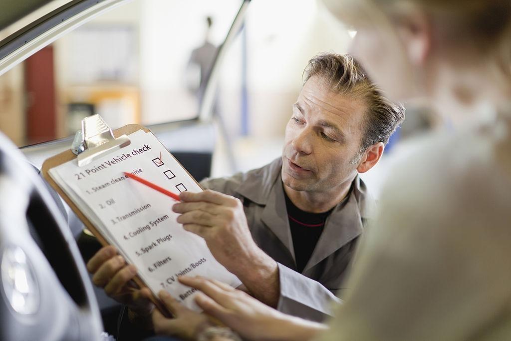 An inspector shows a list of vehicle check to a woman. Ask a professional pre-purchase car inspector in Melbourne to inspect your dream car. Contact German Precision now!