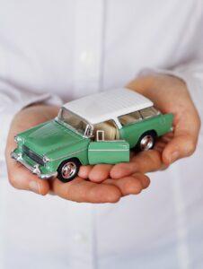 A man holding a small car toy. If you plan to buy a used car, beware of common car selling scams. Hire German Precision for a detailed pre-purchase car inspection!